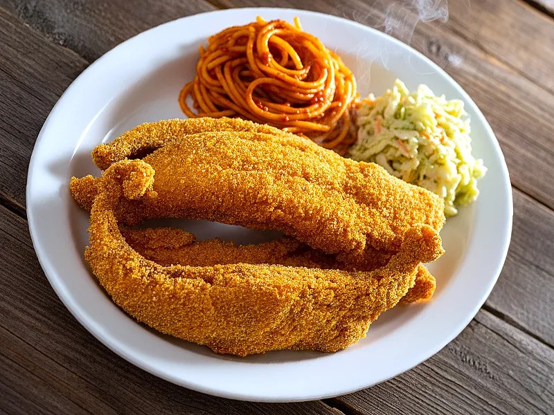 Southern fried catfish with Memphis spaghetti and coleslaw on a white plate